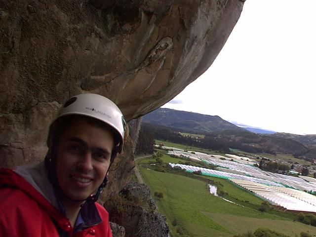 Escalador con casco bajo un techo de roca en Suesca